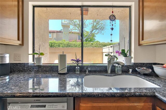 1531 Corte Caballo Unit 33, Upland, CA 91786 - kitchen view of dishwashing machine, brown cabinetry, and dark stone counters