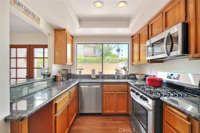 1531 Corte Caballo Unit 33, Upland, CA 91786 - kitchen with appliances with stainless steel finishes, a raised ceiling, brown cabinets, and dark wood finished floors
