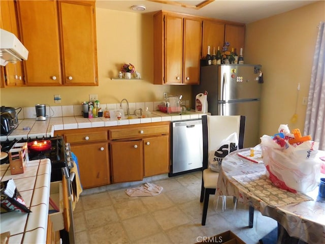 8372 Dogwood Ave, California City, CA 93505 - kitchen featuring stainless steel appliances, tile countertops, exhaust hood, and brown cabinetry