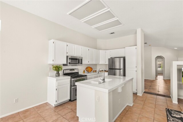 33546 Maplewood Ct, Temecula, CA 92592 - kitchen featuring appliances with stainless steel finishes, arched walkways, light tile patterned flooring, light countertops, and vaulted ceiling