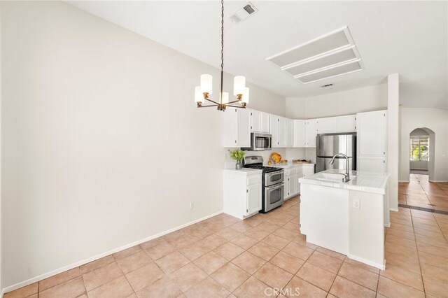 33546 Maplewood Ct, Temecula, CA 92592 - kitchen with stainless steel appliances, arched walkways, light tile patterned flooring, a chandelier, and white cabinets