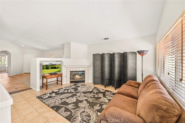 33546 Maplewood Ct, Temecula, CA 92592 - living room featuring arched walkways, tile patterned flooring, lofted ceiling, and a tile fireplace