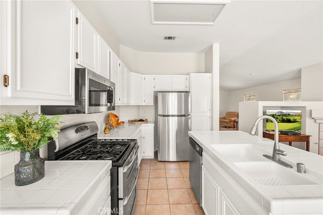 33546 Maplewood Ct, Temecula, CA 92592 - kitchen with appliances with stainless steel finishes, tile counters, and white cabinets