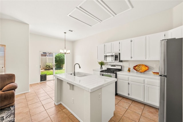 33546 Maplewood Ct, Temecula, CA 92592 - kitchen with appliances with stainless steel finishes, light tile patterned floors, white cabinetry, and a kitchen island with sink