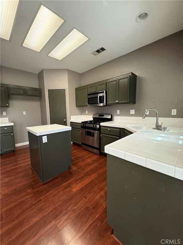 13590 Fox Point Rd, Victorville, CA 92392 - kitchen featuring appliances with stainless steel finishes, tile countertops, dark wood-style floors, a kitchen island, and recessed lighting