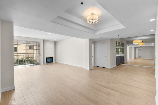 4348 Mammoth Ave Unit 102, Sherman Oaks, CA 91423 - unfurnished living room with a glass covered fireplace, recessed lighting, light wood-type flooring, and a tray ceiling