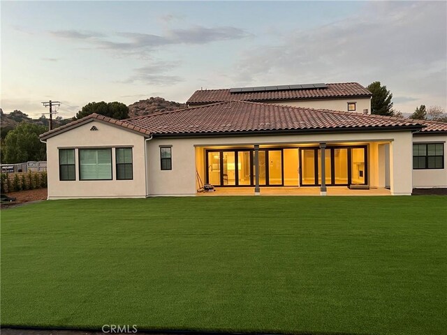 22046 Fig Tree Ln, Chatsworth, CA 91311 - rear view of property featuring solar panels, a lawn, and stucco siding
