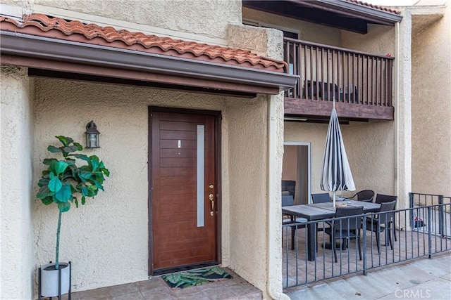 9418 Via Patricia Unit 30, Burbank, CA 91504 - view of exterior entry featuring stucco siding, outdoor dining area, a tiled roof, and a balcony