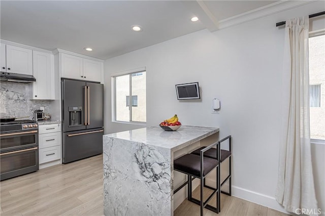 9418 Via Patricia Unit 30, Burbank, CA 91504 - kitchen featuring stainless steel appliances, under cabinet range hood, a kitchen breakfast bar, decorative backsplash, and white cabinetry