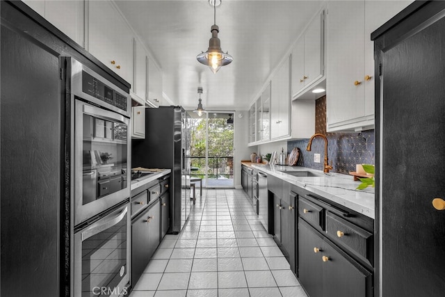 2662 E 2nd St Unit E1, Long Beach, CA 90803 - kitchen with stainless steel appliances, backsplash, white cabinets, light tile patterned floors, and pendant lighting