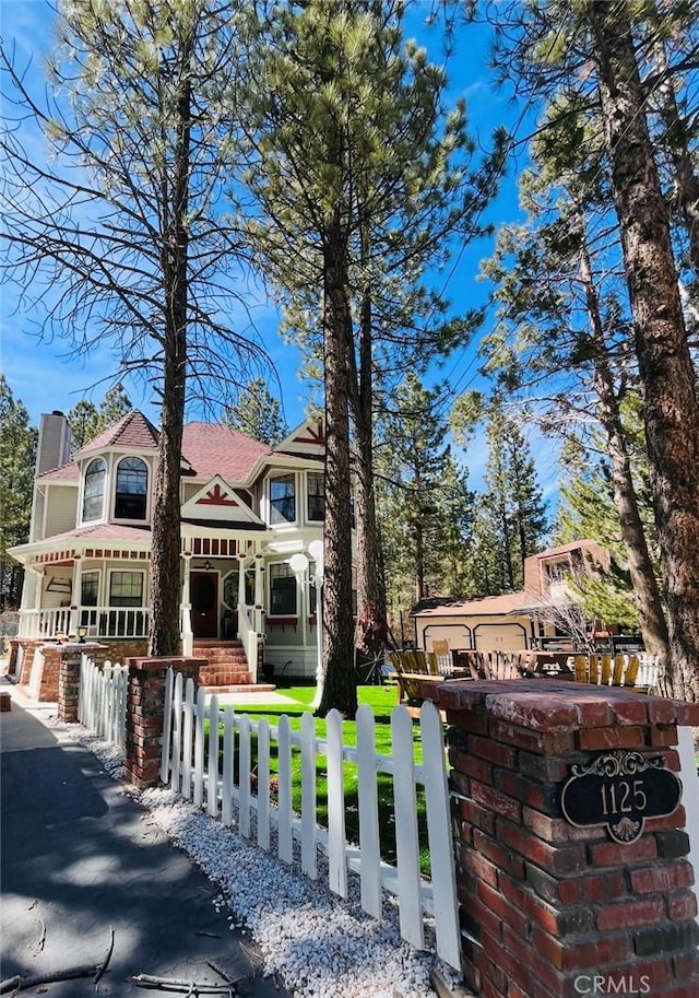 1125 Hemlock Ln, Big Bear City, CA 92314 - victorian-style house featuring a chimney, a fenced front yard, and covered porch
