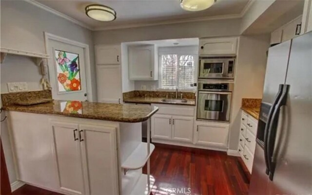 3666 Cedar Ave, Long Beach, CA 90807 - kitchen featuring stainless steel appliances, a peninsula, crown molding, dark wood-style floors, and white cabinets
