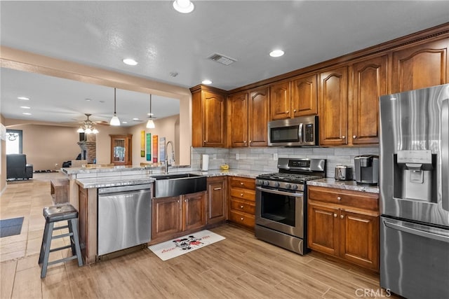 40139 15th St W, Palmdale, CA 93551 - kitchen with appliances with stainless steel finishes, a ceiling fan, open floor plan, brown cabinetry, and recessed lighting