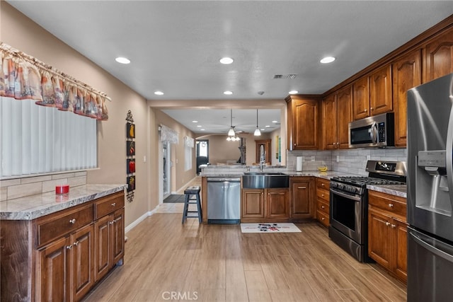 40139 15th St W, Palmdale, CA 93551 - kitchen with stainless steel appliances, light wood finished floors, a peninsula, decorative backsplash, and light countertops