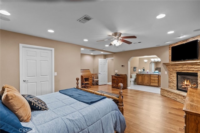 40139 15th St W, Palmdale, CA 93551 - bedroom featuring light wood-style floors, arched walkways, recessed lighting, a fireplace, and connected bathroom