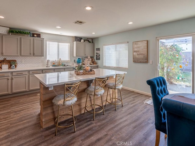3031 E Lingard St, Lancaster, CA 93535 - kitchen with gray cabinetry, backsplash, light countertops, a kitchen breakfast bar, and dark wood-type flooring