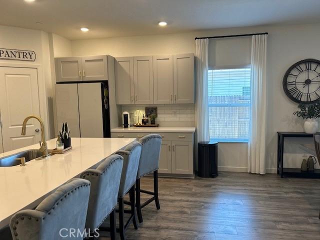 1658 Almondwood Dr, Orland, CA 95963 - kitchen with freestanding refrigerator, gray cabinetry, dark wood-style floors, a kitchen breakfast bar, and decorative backsplash