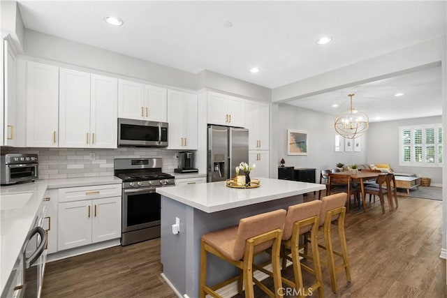 13131 Park Pl Unit 102, Hawthorne, CA 90250 - kitchen with appliances with stainless steel finishes, a kitchen bar, dark wood-style floors, backsplash, and a kitchen island