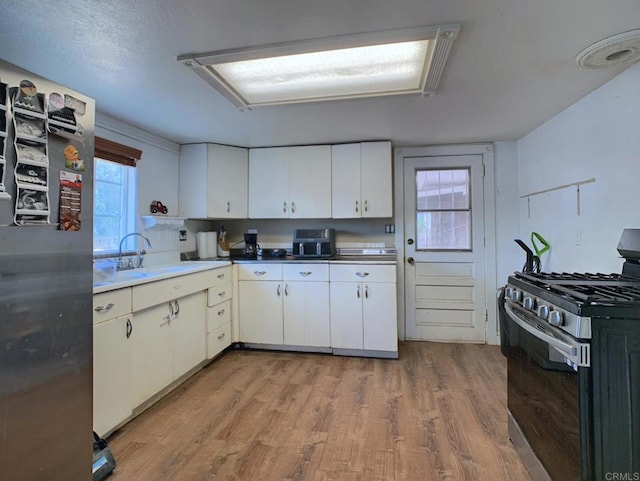 1390 Dewey Pl, Campo, CA 91906 - kitchen featuring stainless steel gas range oven, light wood-style flooring, and white cabinetry