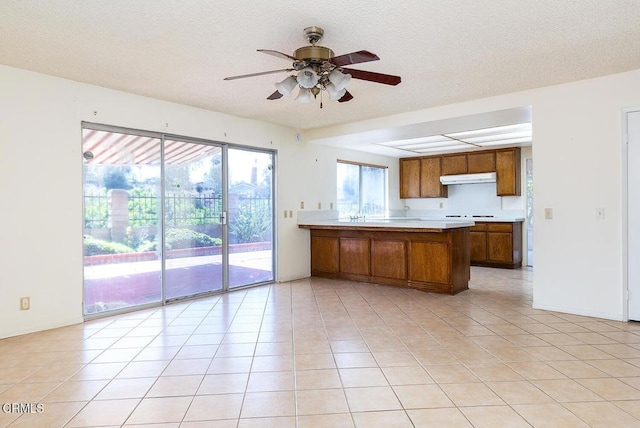2026 Thomas Pl, West Covina, CA 91792 - kitchen with under cabinet range hood, brown cabinetry, a peninsula, light countertops, and ceiling fan