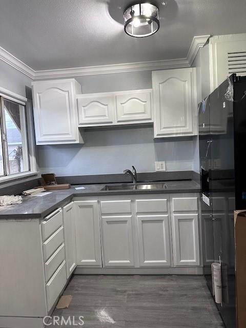 1500 E Wardlow Rd, Long Beach, CA 90807 - kitchen with ornamental molding, dark countertops, white cabinetry, and wood finished floors