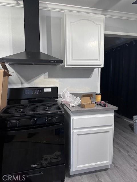 1500 E Wardlow Rd, Long Beach, CA 90807 - kitchen featuring wall chimney range hood, black range with gas stovetop, white cabinets, ornamental molding, and light wood-type flooring