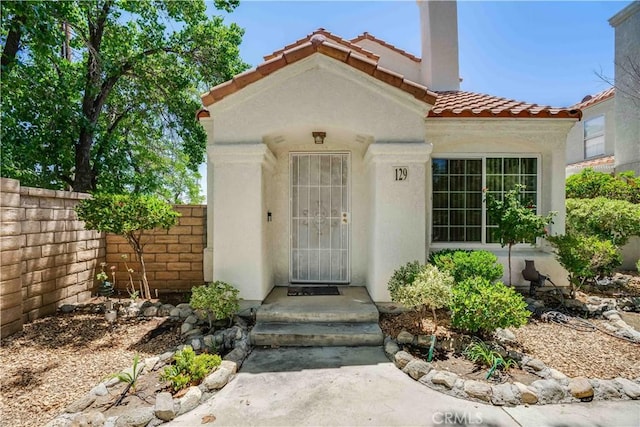 37940 42nd St E Unit 129, Palmdale, CA 93552 - view of exterior entry with a tiled roof, stucco siding, and a chimney
