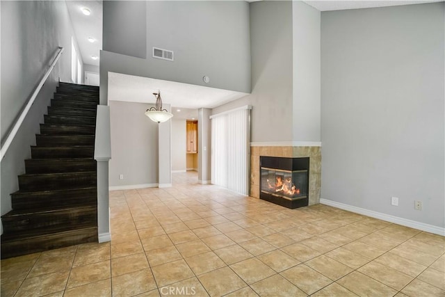37940 42nd St E Unit 129, Palmdale, CA 93552 - unfurnished living room featuring light tile patterned floors, a towering ceiling, stairs, and a fireplace