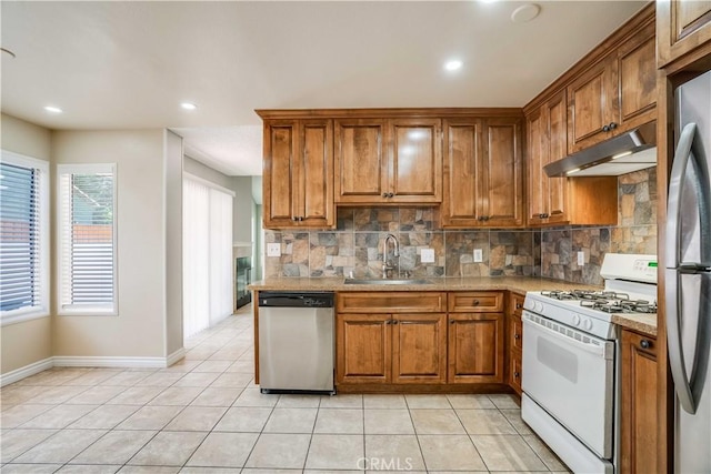 37940 42nd St E Unit 129, Palmdale, CA 93552 - kitchen featuring appliances with stainless steel finishes, under cabinet range hood, brown cabinets, tasteful backsplash, and light countertops