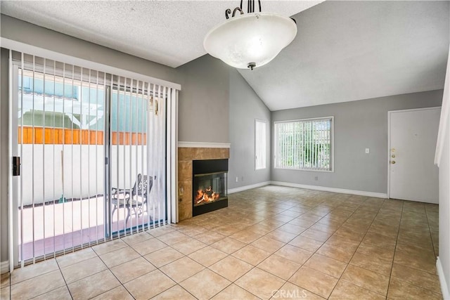 37940 42nd St E Unit 129, Palmdale, CA 93552 - unfurnished living room featuring tile patterned flooring, vaulted ceiling, a tiled fireplace, and a textured ceiling