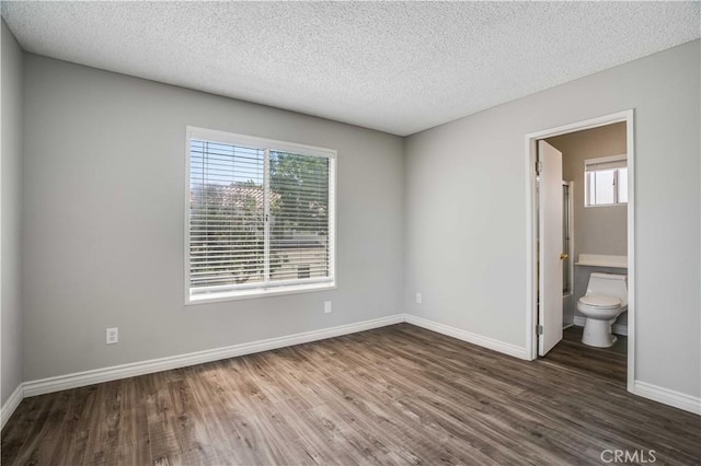 37940 42nd St E Unit 129, Palmdale, CA 93552 - unfurnished bedroom with wood finished floors, multiple windows, a textured ceiling, and ensuite bath