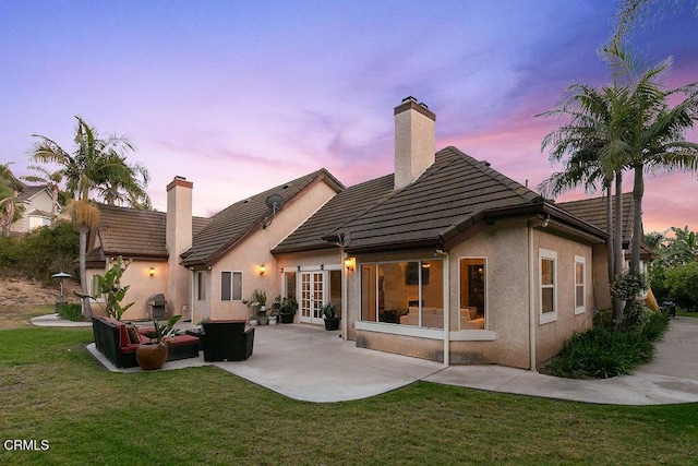 2981 Yucca Dr, Camarillo, CA 93012 - back of property at dusk with a chimney, a yard, french doors, a patio area, and an outdoor hangout area