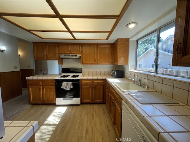 1039 Maple St, Arroyo Grande, CA 93420 - kitchen with gas stove, tile countertops, brown cabinetry, light wood-type flooring, and under cabinet range hood