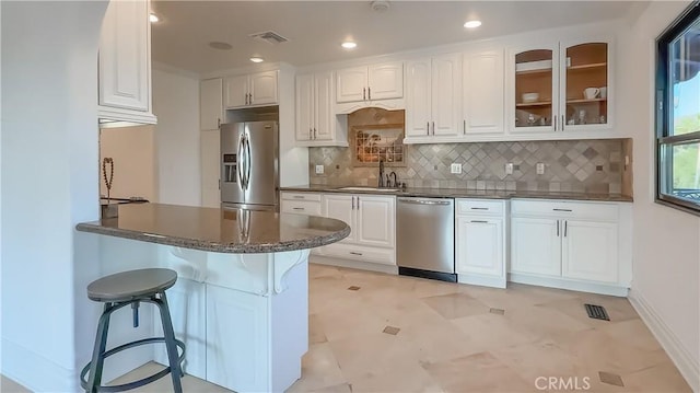 567 Lone Oak Dr, Thousand Oaks, CA 91362 - kitchen featuring appliances with stainless steel finishes, white cabinetry, glass insert cabinets, a kitchen bar, and tasteful backsplash
