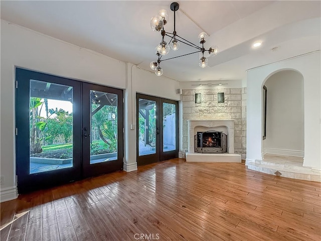 567 Lone Oak Dr, Thousand Oaks, CA 91362 - unfurnished living room featuring french doors, hardwood / wood-style floors, arched walkways, and a lit fireplace
