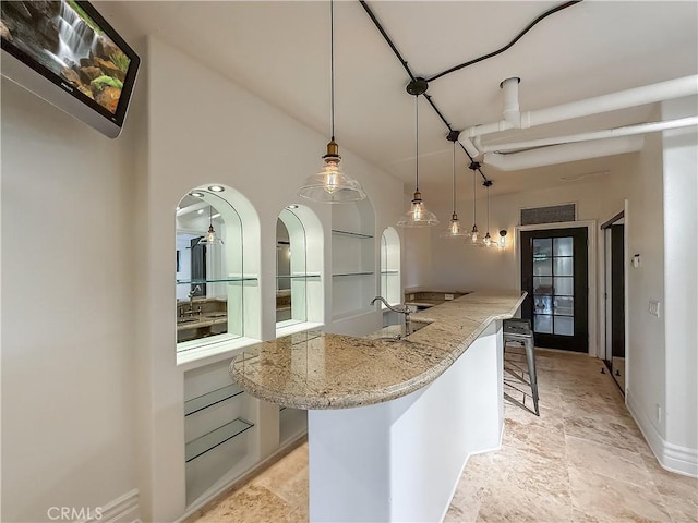 567 Lone Oak Dr, Thousand Oaks, CA 91362 - kitchen with arched walkways, light stone countertops, pendant lighting, a kitchen breakfast bar, and an island with sink