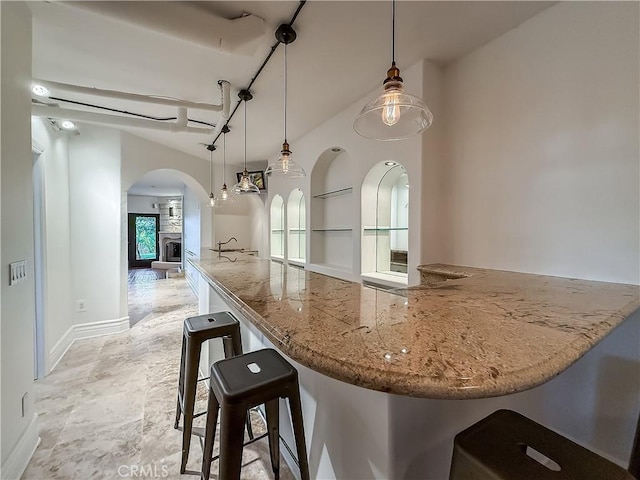 567 Lone Oak Dr, Thousand Oaks, CA 91362 - kitchen with arched walkways, light stone countertops, hanging light fixtures, a breakfast bar area, and open floor plan