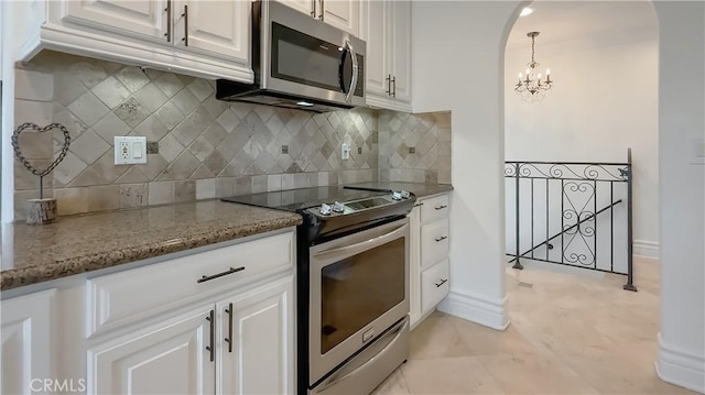 567 Lone Oak Dr, Thousand Oaks, CA 91362 - kitchen featuring stainless steel appliances, white cabinetry, a chandelier, tasteful backsplash, and stone countertops