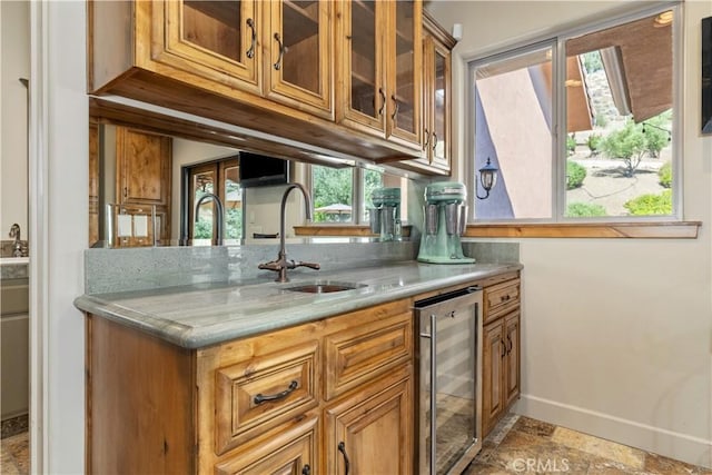9942 Sunfish Cir, Paso Robles, CA 93446 - kitchen featuring beverage cooler, brown cabinetry, glass insert cabinets, and light stone countertops