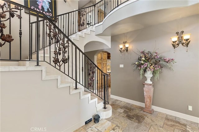 9942 Sunfish Cir, Paso Robles, CA 93446 - stairway with arched walkways, a chandelier, stone tile floors, and a towering ceiling