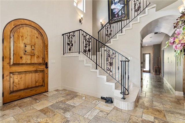 9942 Sunfish Cir, Paso Robles, CA 93446 - entryway featuring stone tile flooring, arched walkways, stairs, and a towering ceiling