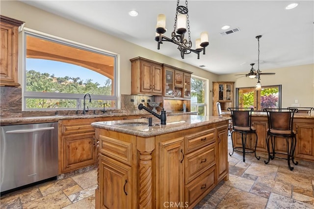 9942 Sunfish Cir, Paso Robles, CA 93446 - kitchen featuring stainless steel dishwasher, stone tile floors, tasteful backsplash, an island with sink, and decorative light fixtures