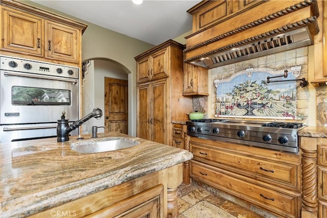 9942 Sunfish Cir, Paso Robles, CA 93446 - kitchen featuring stainless steel appliances, custom exhaust hood, arched walkways, light stone counters, and brown cabinetry