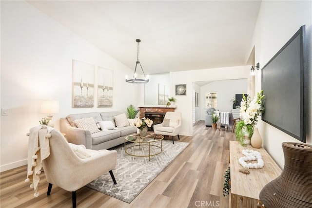 6772 Rook Dr, Huntington Beach, CA 92647 - living area with lofted ceiling, light wood-style floors, a chandelier, and a brick fireplace
