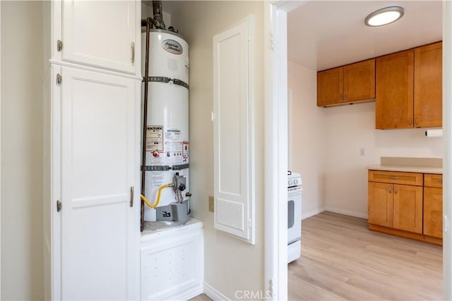 1534 W 154th Pl, Gardena, CA 90247 - kitchen featuring strapped water heater, light wood-type flooring, white stove, brown cabinetry, and light countertops