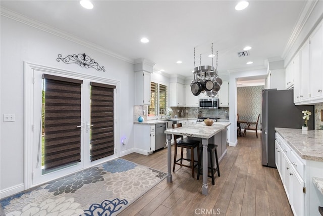 3720 Gunnison Cir, Corona, CA 92881 - kitchen with stainless steel appliances, a center island, white cabinets, backsplash, and crown molding