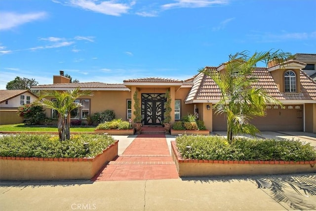 2335 N San Antonio Ave, Upland, CA 91784 - mediterranean / spanish-style house with stucco siding, concrete driveway, a garage, a chimney, and a tiled roof