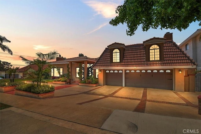 2335 N San Antonio Ave, Upland, CA 91784 - view of front of property with a tiled roof, a garage, driveway, a chimney, and stucco siding