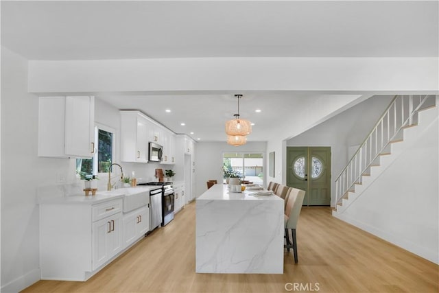 801 Navajo Dr, Riverside, CA 92507 - kitchen with stainless steel appliances, white cabinetry, light wood-style floors, a center island, and recessed lighting