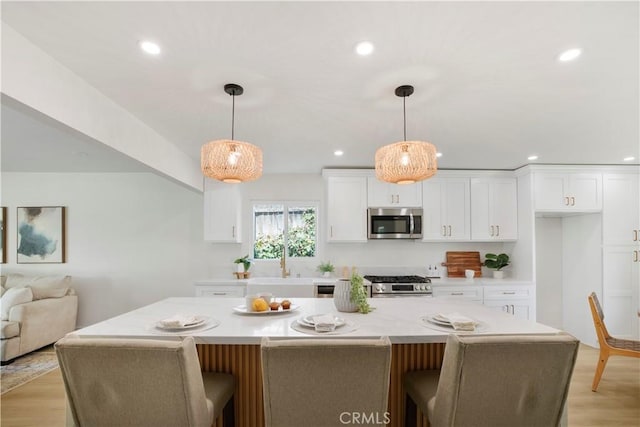 801 Navajo Dr, Riverside, CA 92507 - kitchen with appliances with stainless steel finishes, white cabinetry, light countertops, recessed lighting, and a kitchen bar